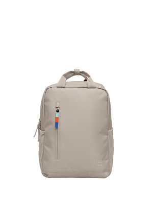 Zaino rettangolare beige con maniglia superiore, tasca frontale verticale con cerniera e tiretto multicolore, e tasche laterali, etichettato "SOT BAG."