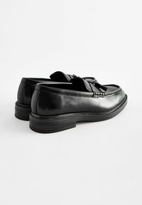 Sorte læder loafers med en glat finish, dekorative kvaster og en stablet gummisål. Kontrastsyning langs den øverste kant.