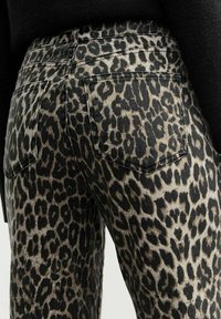 Jeans i leopardmönster i beige och svart färgkombination. Har bakfickor och ett strukturerat tyg med synlig sömnad.