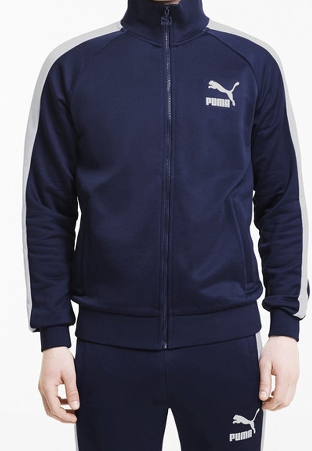 Námořnická sportovní bunda s vysokým límcem, plným zipem a šedými bočními akcenty. Vyrobena z hladkého materiálu s logem na hrudi.