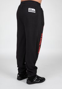 Sorte joggers med waffle-tekstur har et rødt "OLD SCHOOL SERIES" print langs siden, elastisk talje og to sidelommer.