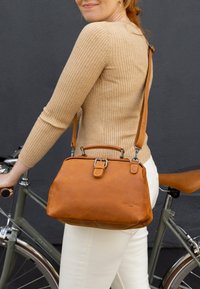 Brown leather handbag with a structured design, detachable shoulder strap, and top handle. It features a smooth texture and silver hardware accents.
