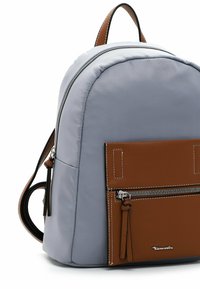 Sac à dos en tissu gris doux avec des accents en cuir marron. Il dispose d'une poche zippée à l'avant et d'une forme arrondie avec des bretelles réglables.
