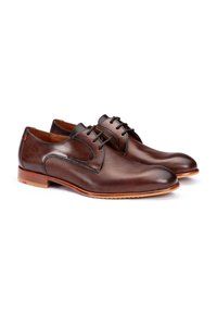 Scarpe eleganti in pelle marrone con una superficie liscia, sottile texture a righe, design con lacci e una suola in legno marrone chiaro. Dettaglio rosso vicino al tallone.