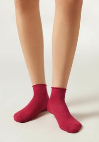 Calcetines tobilleros burdeos hechos de una tela suave con una textura lisa. Tienen un ajuste ceñido y un diseño minimalista, adecuados para el uso casual.