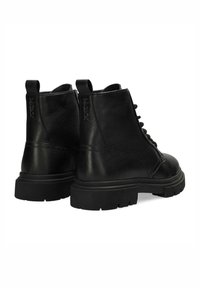 Botas de tobillo de cuero negro con un acabado texturizado, punta redonda, suela de goma gruesa y cierre con cordones. Presentan tiradores en el talón.
