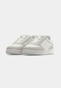 Lichtgrijze en witte sneakers met een mix van glad leer en suède. Geperforeerde neus, gevoerde kraag, platte veters en een rubberen buitenzool.