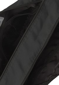 Interno di una borsa in nylon nera con due compartimenti zip, uno con dettagli in rete. Texture liscia, cuciture rinforzate e zip robuste.