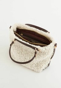 Torba o fakturze w kolorze kremowym z puszystą powierzchnią i brązowymi skórzanymi akcentami. Posiada zamek błyskawiczny i wnętrze z przegrodami.