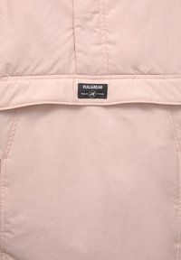 Svetloružový prešívaný kabátik s čiernym štítkom Pull&Bear, na ktorom je vyšitý nápis "Navrhnuté v Európe".