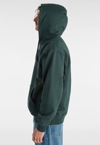 Felpa verde con tasca frontale, cappuccio con cordino e polsini a coste. Presenta una vestibilità rilassata e un tessuto morbido e testurizzato.