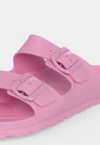 Ροζ λαστιχένια σανδάλι με δύο ρυθμιζόμενες αγκράφες και υφή στην σόλα, σχεδιασμένο για καθημερινή χρήση και άνετη εφαρμογή.