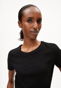 Sort ribbet kortærmet t-shirt med rund halsudskæring. Stoffet har en glat tekstur, der fremhæver en tætsiddende silhuet.