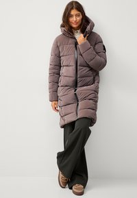 Abrigo acolchado hasta la rodilla en malva suave con un cuello alto y cierre de cremallera. Incluye una capucha y un gran patrón de acolchado horizontal.