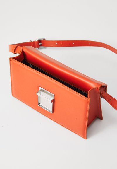 Oranžová kožená crossbody taška se stříbrným kováním, obdélníkového tvaru, plochého designu a zipovou přihrádkou. Obsahuje nastavitelný popruh.