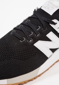 Scarpa da uomo nera per attività sportive con tomaia in rete, dettagli bianchi, logo 'N' in evidenza e lacci neri. Presenta una suola testurizzata e un design leggero.