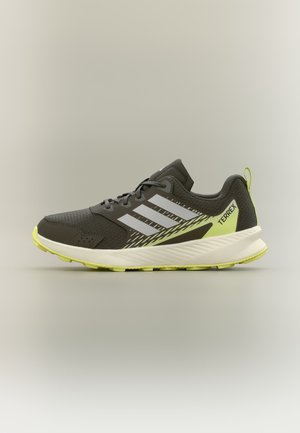 Chaussure de course Adidas Terrex gris foncé et jaune fluo avec semelle blanche et trois bandes blanches sur le côté, vue de profil.