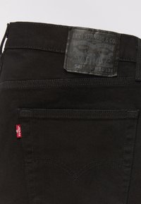 Poche arrière d'un jean Levi's noir avec une étiquette rouge Levi's visible et un patch en cuir de la marque indiquant la taille 34x34 et le modèle 541.