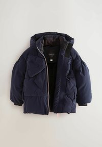 Námornícky puffer kabát s kapucňou, s predným zipsom, náprsníkovými vreckami a textúrovanými detailmi na rukávoch. Vyrobený z prešívaného, syntetického materiálu.
