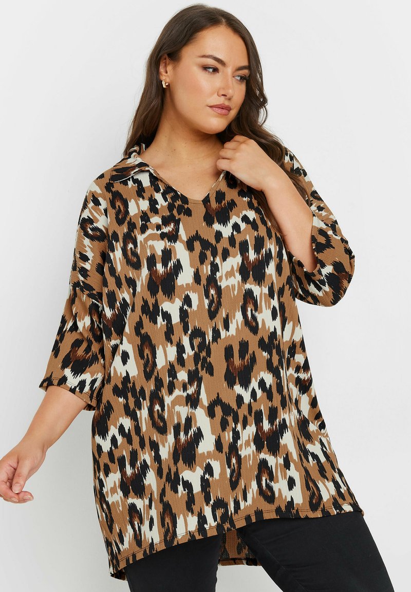 Camicia con stampa leopardata in marrone e crema, con colletto, maniche a tre quarti e vestibilità ampia, caratterizzata da un orlo posteriore più lungo.