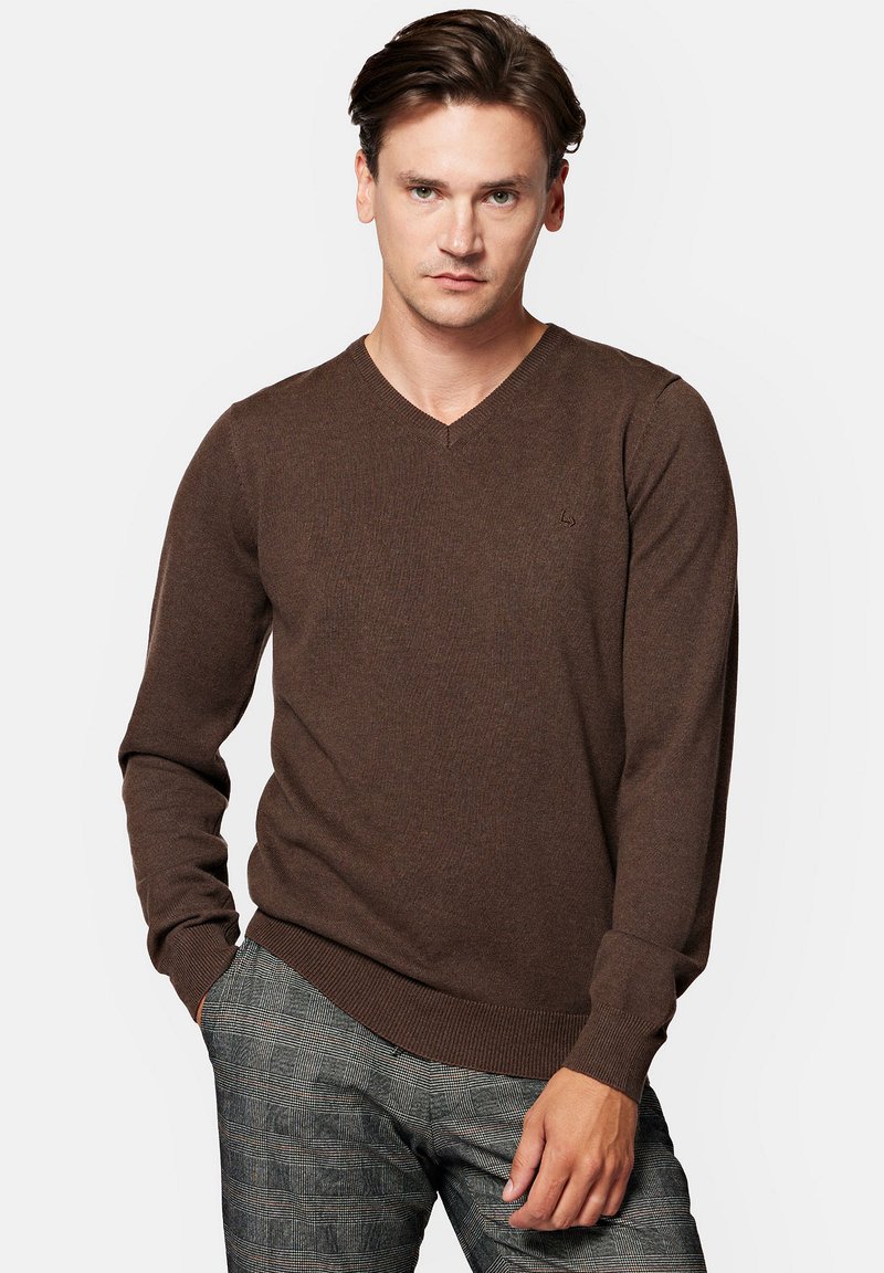 Brązowy sweter w serek z długimi rękawami, z prążkowanymi mankietami i dołem. Wykonany z miękkiego materiału o delikatnej fakturze. Zawiera mały detal w postaci logo na klatce piersiowej.