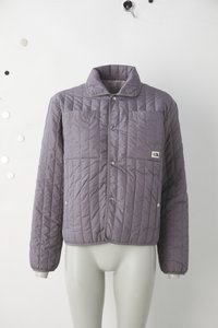 Μπλε μπουφάν με ραφές σχήματος καρώ, εμπρός με κεντρωτά κουμπιά, δύο τσέπες στο στήθος και απαλό γιακά. Διαθέτει διαγώνιες ραφές και ετικέτα με λογότυπο.