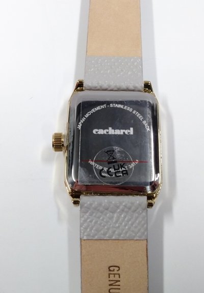 Vierkante gouden horlogekast met beige leren band met structuur, merk "cacharel", en zichtbare tekst "Japan movement - roestvrijstalen achterkant".