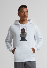 Hvid hoodie lavet af bomuldsblanding med et farverigt grafik af en karakter iført grå hoodie og bukser. Design med kengurulomme.