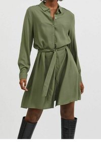 Klänning med lång ärm och knappar i olivgrönt, åtsmala vid midjan med ett knytbälte, gjord av slät tyg, med krage och flytande kjol.