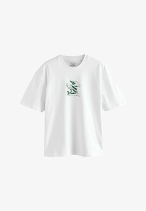 Valge puuvillane T-särk, millel on ees roheline trükk trompetliiliate kujutisega, lühikeste varrukatega ja mugava lõikega.