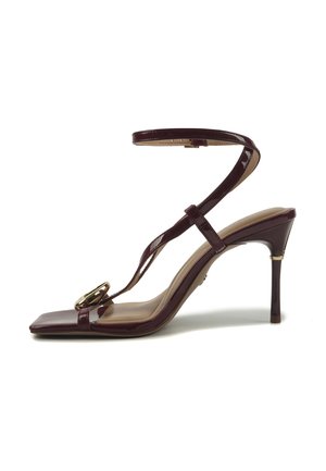 Tmavé bordové sandále na vysokom opätku s remienkom okolo členka, štvorcovou špičkou a dekoratívnou zlatou prackou na prednom remienku.