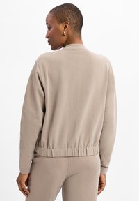 Lichtbeige sweatshirt met een ontspannen fit, ribgebreide mouwen en een gathered zoom. Gemaakt van zachte stof met een gladde textuur.
