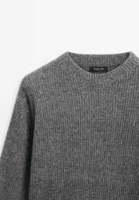 Pull en maille côtelée grise avec col rond, avec l'étiquette de la marque Massimo Dutti à l'intérieur du col.