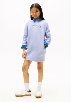 Vestido sudadera morado con logo bordado, mangas de mezclilla enrolladas y un ajuste cómodo, combinado con zapatillas blancas y calcetas altas.