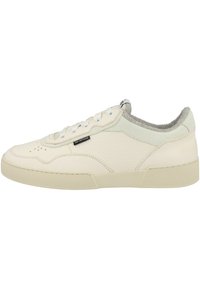 Textured cream leather sneaker with perforated details, gray suede accents at the heel, and a rubber sole. Features white laces and tongue.