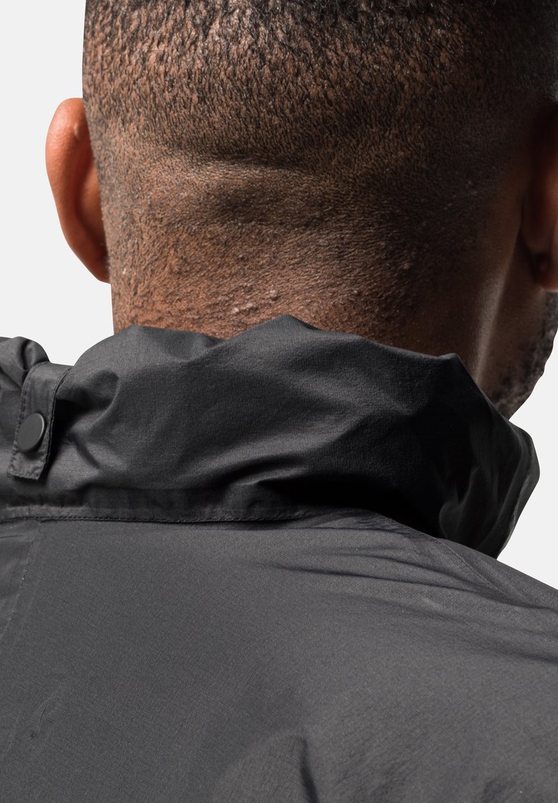 Schwarze Jacke mit hohem Kragen und strukturiertem Stoff. Enthält einen Druckknopfdetail, das eine glatte und leicht glänzende Oberfläche zeigt.