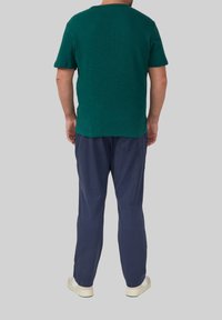Groene gestructureerde T-shirt met korte mouwen, gecombineerd met donkerblauwe broeken, met een relaxte pasvorm en casual witte sneakers.