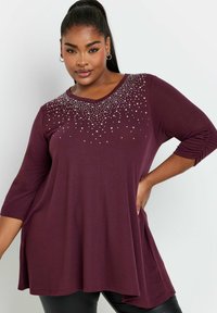 Maglia a maniche lunghe bordeaux con scollatura a V, impreziosita da una gradazione di borchie argentate, caratterizzata da una vestibilità ampia e dettagli con maniche arricciate.