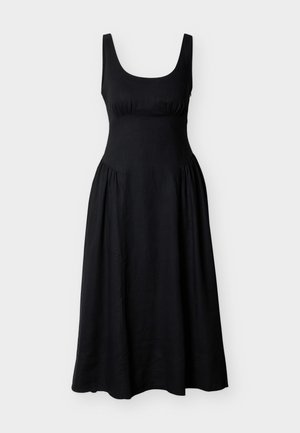 Vestido midi negro sin mangas con cuerpo ajustado, escote redondo y falda fruncida sobre un fondo claro y sencillo.