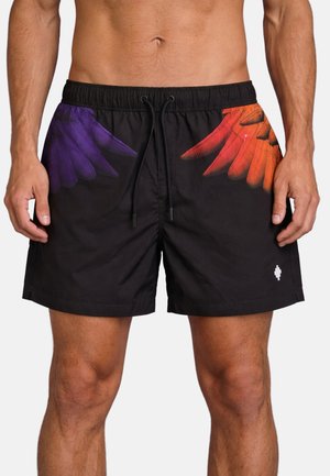 Torso e gambe maschili che indossano pantaloncini neri con coulisse, decorati con disegni di ali di piume viola e arancioni sui lati e un piccolo logo bianco sulla gamba sinistra.