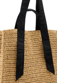 Borsa tote in paglia intrecciata con manici piatti in tessuto nero e marchio impresso, forma strutturata e finitura naturale testurizzata.