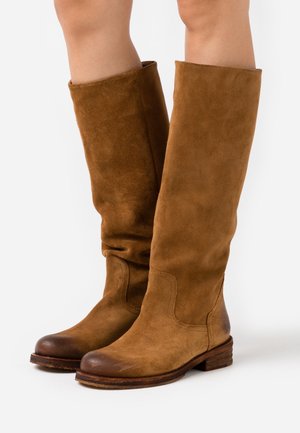 Stivali alti in suede marrone con punta rotonda, parte superiore morbida e tacco basso impilato. Presentano una texture morbida e dettagli di cucitura sottili.