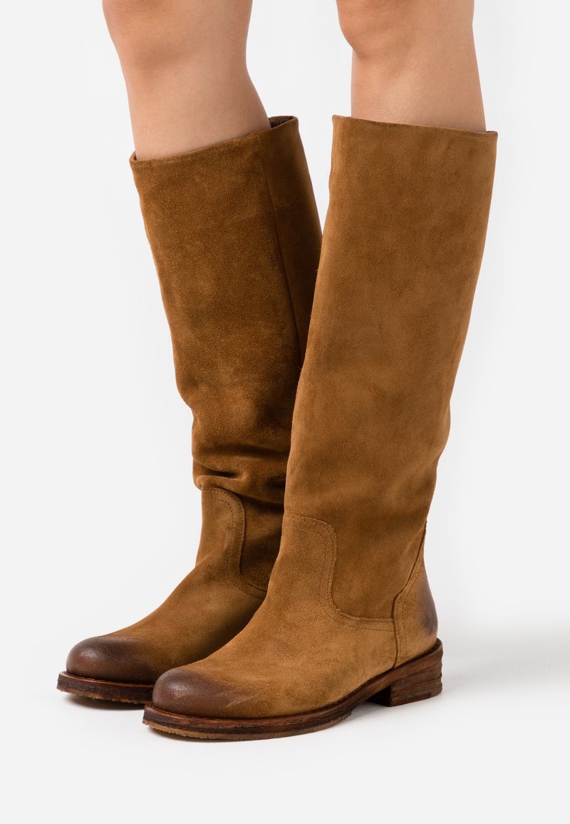 Stivali alti in suede marrone con punta rotonda, parte superiore morbida e tacco basso impilato. Presentano una texture morbida e dettagli di cucitura sottili.