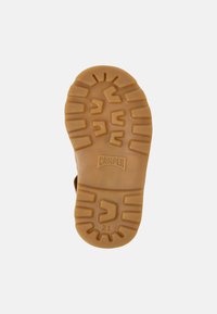 Semelle de chaussure en caoutchouc de couleur brun clair, avec un motif de grip texturé présentant des rainures et la marque "Camper" embossée. Comprend la taille "21."