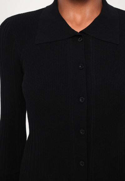 Černý žebrovaný kardigan s dlouhými rukávy, velkým límcem a sedmi černými knoflíky vpředu. Jemná textura a přiléhavý střih.