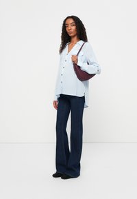 Light blue, striped button-up shirt with pockets; dark blue, flared denim pants; small, maroon handbag; black flat shoes.