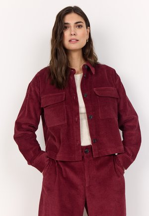 Burgundy corduroy jacket with two chest pockets, button closure, and a slightly cropped design, paired with matching pants.