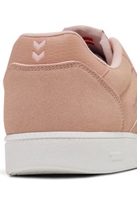 Baskets en daim rose avec un dos texturé, une semelle en caoutchouc blanche et des détails accentués roses. Dotées de deux ornements en forme de chevrons près du talon.