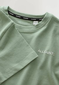 Svetlozelené tričko s krátkym rukávom a okrúhlym výstrihom. Na hrudi je biely nápis "ALLSAINTS" a na vnútornej strane čierna etiketa. Mäkká látka.