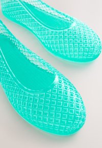 Skaidrios akvamarino spalvos baleto bateliai su tekstūruotu deimanto raštu, apvalia nosimi, lanksčia medžiaga ir lygiu vidumi.